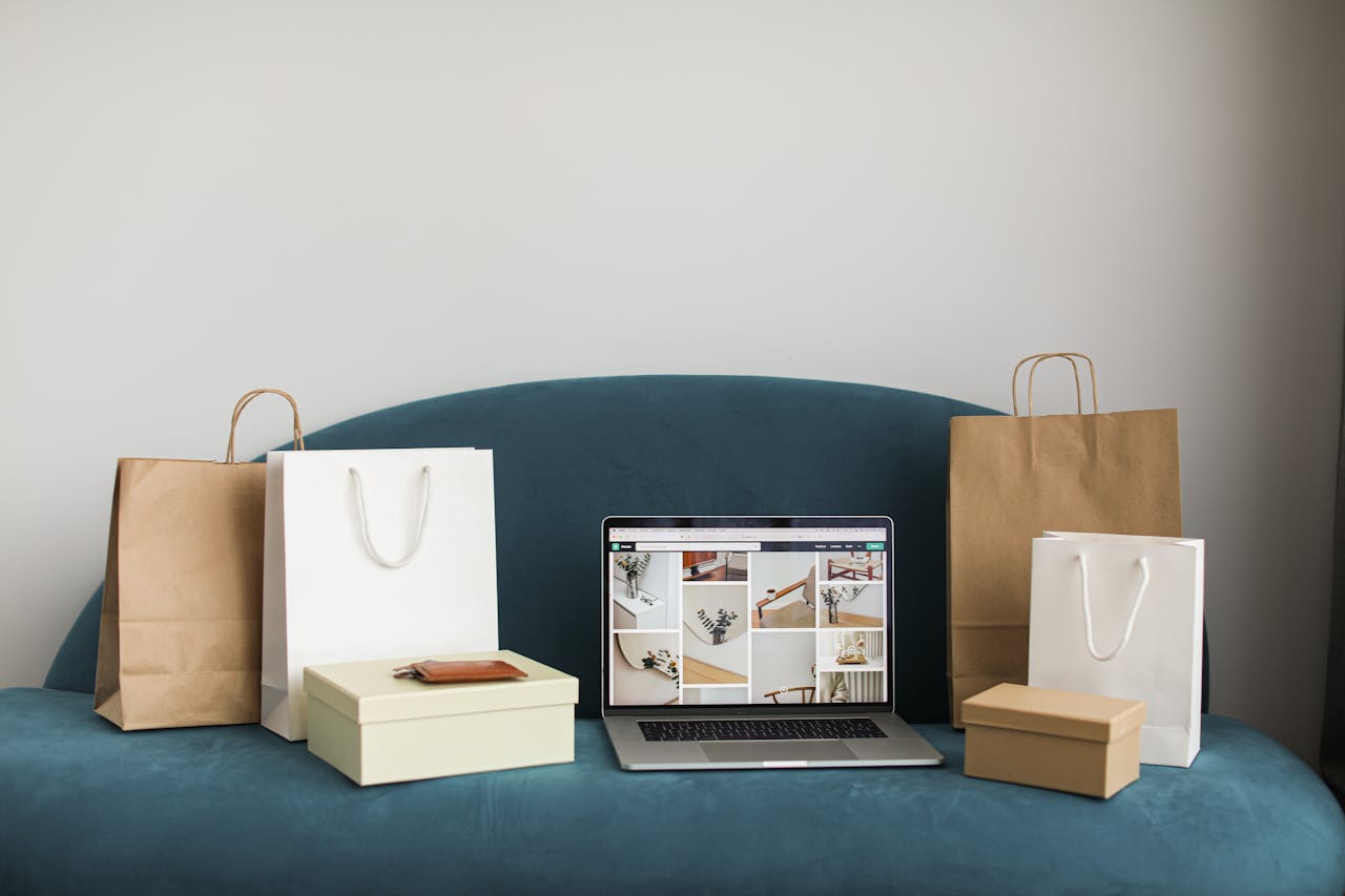 services-01 A laptop surrounded by shopping bags and boxes on a blue sofa, ideal for online shopping themes.