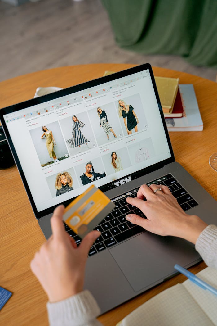 about-02 A woman makes an online purchase using a credit card on her laptop, browsing an online fashion store.